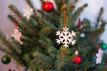 a Christmas tree decorated with a white snowflake ornament, red baubles, and festive hanging figures