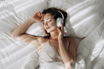 Woman, headphones and happy on bed, relax and eyes closed with streaming subscription in home. Girl, person and smile with audio tech, sound and listening to music