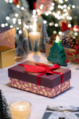 A pink gift box with red bow ribbon on table, Christmas festive decoration atmosphere and celebration ambiance with bokeh light illimitation in background.