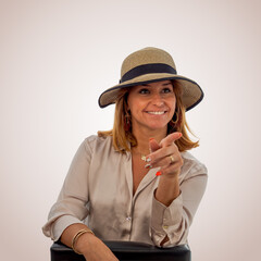 Smiling woman in summer hat pointing at the camera