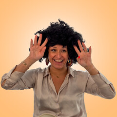 Cheerful woman making funny gesture with hands and curly wig