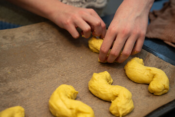 Female working and mixing dough for baking s-shaped yellow pastries, traditional Scandinavian holiday bakery