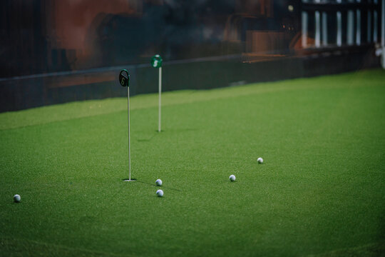 Indoor golf putting green with multiple golf balls and flags, showcasing a vibrant artificial turf environment for recreational activities - Powered by Adobe
