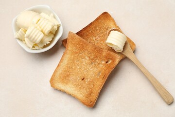 Slices of toasted bread and butter on beige table, flat lay