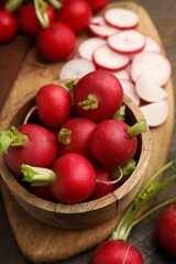 Fresh radishes in bowl on wooden table, closeup