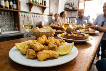 Caz&oacute;n en adobo frito servido con lim&oacute;n en un bar t&iacute;pico andaluz, acompa&ntilde;ado de vino blanco y pan en un ambiente tradicional de tapas.