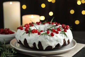 Tasty Christmas cake with cranberries and rosemary on table against blurred lights, closeup