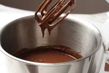 Chocolate dough dripping from mixer into bowl, closeup