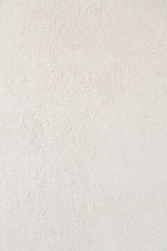 Close-up view of a light, neutral-toned textured wall with subtle grain and organic plaster pattern. Minimalistic background for interior design concepts, mockups.