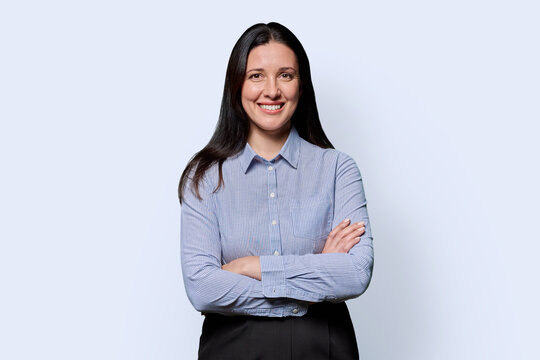 Portrait of confident businesswoman looking at camera, light studio background
