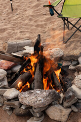 Nighttime Gathering Around Warm Fire On Coast, Calm Night Scene With Flames And Chairs Near Water