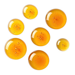 A collection of luminous golden yellow oil or honey droplets floating on a stark black background.