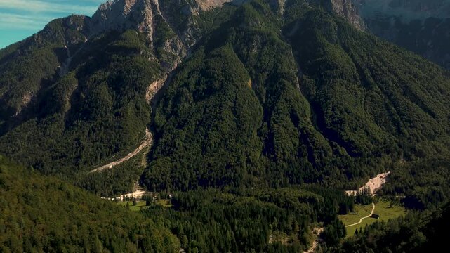 Expansive view of rugged Slovenian mountains south of Kranjska Gora, featuring dense green forests, rocky peaks, and deep alpine valleys under clear skies. 4k stock video