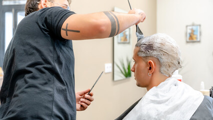 Barber applies hair bleach in modern barbershop