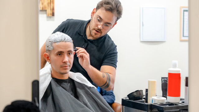 Barber bleaching hair at modern barbershop