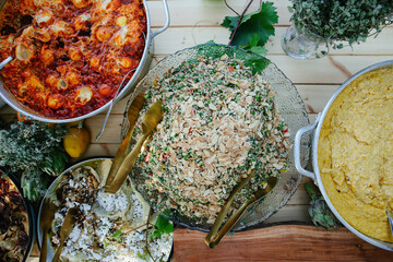Full Overhead Flat Lay of a Colorful Mediterranean Mezze Buffet Spread Featuring Hummus, Tomato Salsa, Olives, and Fresh Citrus Fruits and Shakshuka on a Rustic Table
