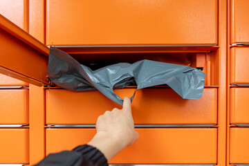 Hand retrieving a package from an automated parcel locker