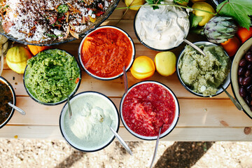 Overhead Flat Lay of a Vibrant Mediterranean Buffet Spread Featuring Hummus, Salsas, Olives, Dips, and Fresh Citrus Fruits