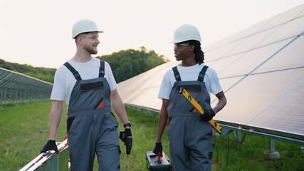 Multiethnic solar panel technicians walking and talking together - Powered by Adobe