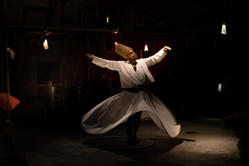 The image of a dervish performing a whirling dervish dance against a dark backdrop.