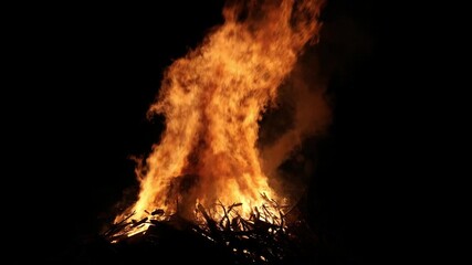 bonfire flames rising into dark night sky (bon fire flame orange yellow red glow glowing ember) sticks wood stick brush wooden fuel summer ceremony celebration enormous huge rise heat campfire camping