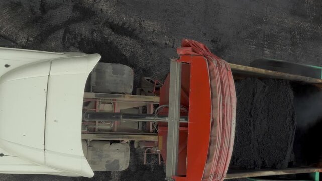Top view of a tipper truck unloading hot asphalt on a construction site for road renewal