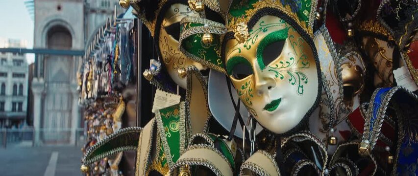 Traditional jester masks with ringing bells display at carnival event on St Mark Square. Festive accessories to hide face sold at masquerade in city. Anamorphic lens