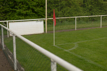 A bright corner flag on a soccer field, surrounded by vibrant green grass, creating a stunning, picturesque scene © Alena