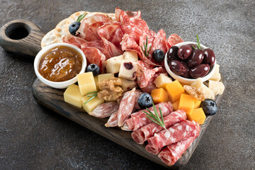 Close-up of charcuterie board with assorted cheeses, meats, olives, jam, crackers and berries. 