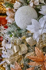 Christmas tree adorned with shimmering decorations, featuring white flowers, golden ribbons, and sparkling ornaments, creating a festive and enchanting holiday atmosphere with bokeh lights