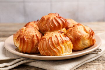 Tasty profiteroles on wooden table, closeup. Delicious dessert