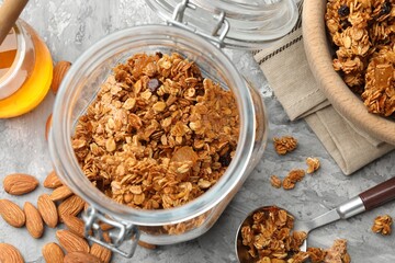 Tasty granola in glass jar and ingredients on light grey table, flat lay