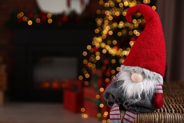 Fototapeta premium Funny Christmas gnome in decorated room, closeup. Space for text