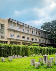 Fototapeta premium Modern Institutional Building Facade with Balconies, Surrounded by Lush Greenery and Grass Field