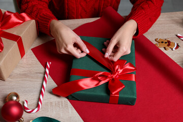Woman wrapping Christmas gift at wooden table, closeup