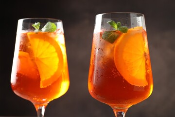 Glasses of refreshing spritzer cocktail on dark background, closeup