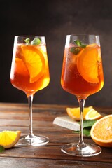 Glasses of refreshing spritzer cocktail and oranges on wooden table