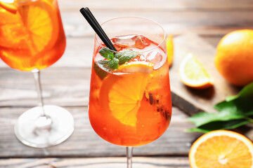 Glasses of refreshing spritzer cocktail and oranges on wooden table, closeup