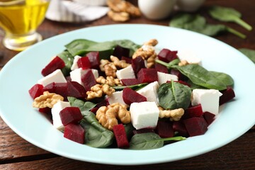 Delicious salad with beetroot, feta cheese, spinach and walnuts on wooden table, closeup