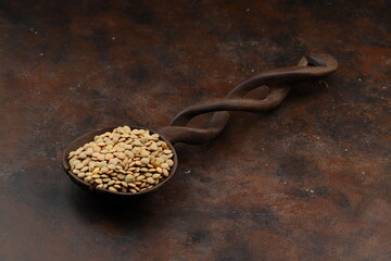 Pile lentil in wooden spoon isolated on Woden background. Top view.
