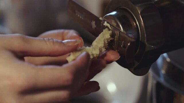 Female hands making dough for traditional Scandinavian Danish Christmas cookies called Vanilla rings, dough getting pushed out for kitchen machine. desaturated footage easily color matched