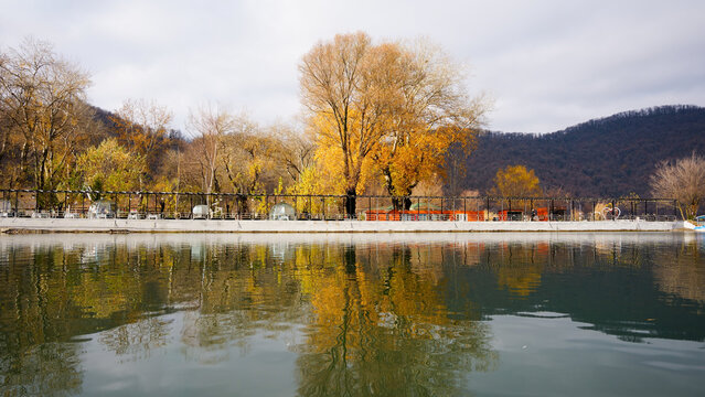 Autumn lakeside seating area - Reflections of golden trees and outdoor seating along a lake in Gabala during late autumna