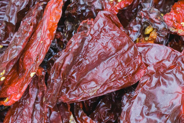 Dried red peppers are displayed in close view highlighting their wrinkled texture and vibrant color...