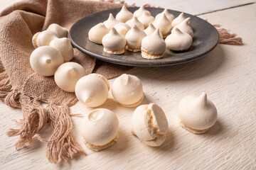 Sweet meringue, a Brazilian sweet called suspiro made with egg whites and sugar, positioned on rustic fabric and accessories, selective focus.