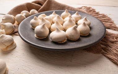 Sweet meringue, a Brazilian sweet called suspiro made with egg whites and sugar, positioned on rustic fabric and accessories, selective focus.