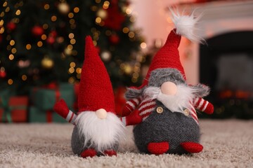 Fototapeta premium Cute Christmas gnomes on floor against blurred lights indoors, closeup
