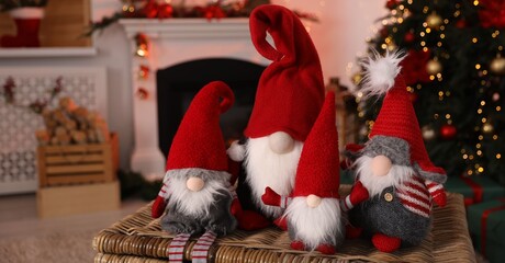 Obraz premium Cute Christmas gnomes on wicker box against blurred lights indoors, closeup. Space for text