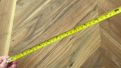 Female hands extending and retracting a floral tape measure on a wooden table. Measurement and DIY concept filmed in 4K with natural light.