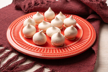 Sweet meringue, a Brazilian sweet called suspiro made with egg whites and sugar, positioned on rustic fabric and accessories, selective focus.
