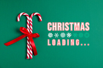 Christmas expectation. Snowflakes as loading bar. Candy canes with red bow on green background, top view